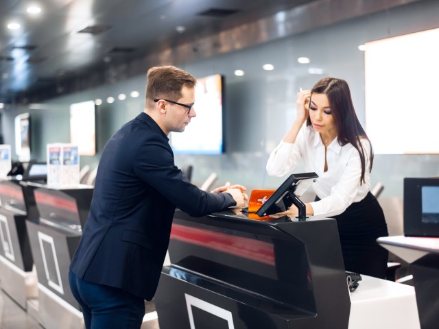 Airline passenger speaking with check-in agent at airport