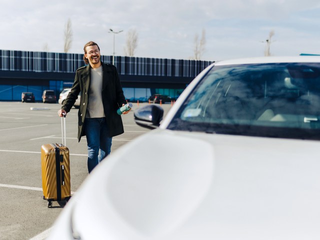 Traveler with suitcase walking toward rental car