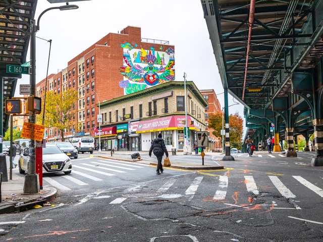 Pedestrian crossing street under elevated railway in the Bronx, New York City