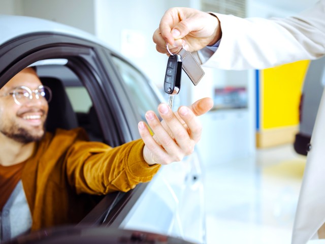 Rental car company employee handing customer keys