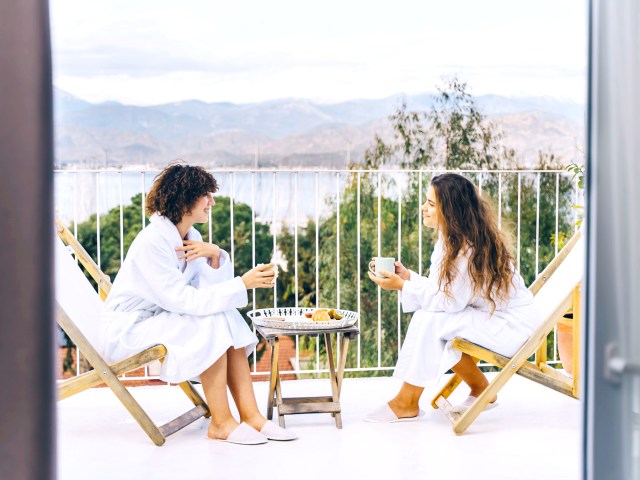 Guests sitting on hotel room balcony overlooking lake