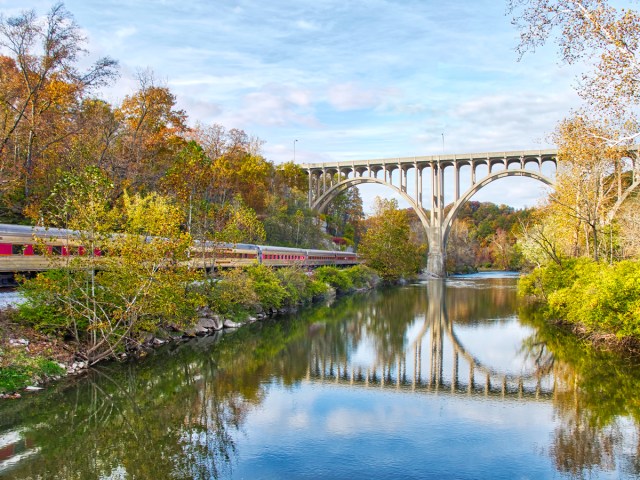 Train passing under bridge beside river in Akron, Ohio