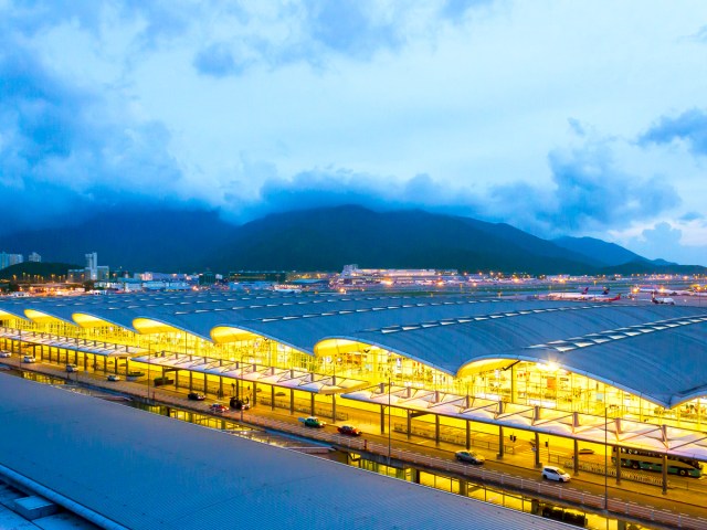 Terminal at Hong Kong International Airport lit at night with mountains in background