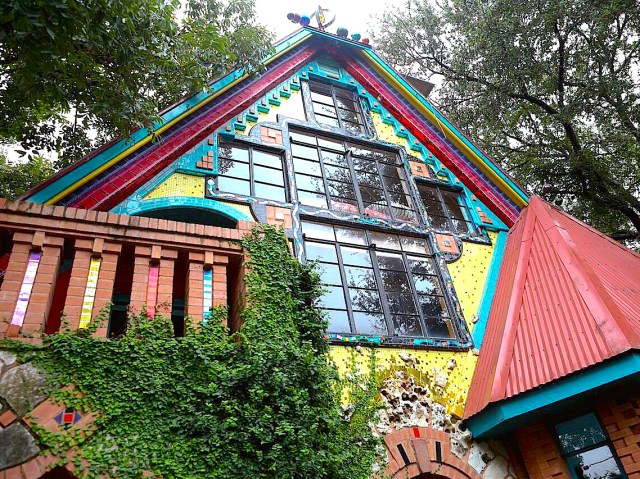 View of Casa Neverlandia's colorful exterior framed by trees in Austin, Texas