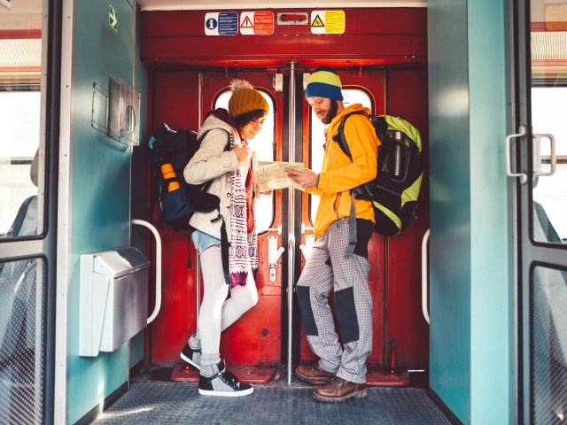 Train passengers standing at doorway reading map