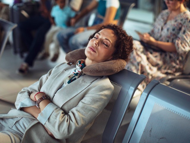 Woman resting with inflatable pillow in airport gate area