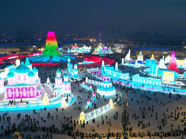 Aerial view of festival attendees admiring ice sculptures illuminated in bright colors at night