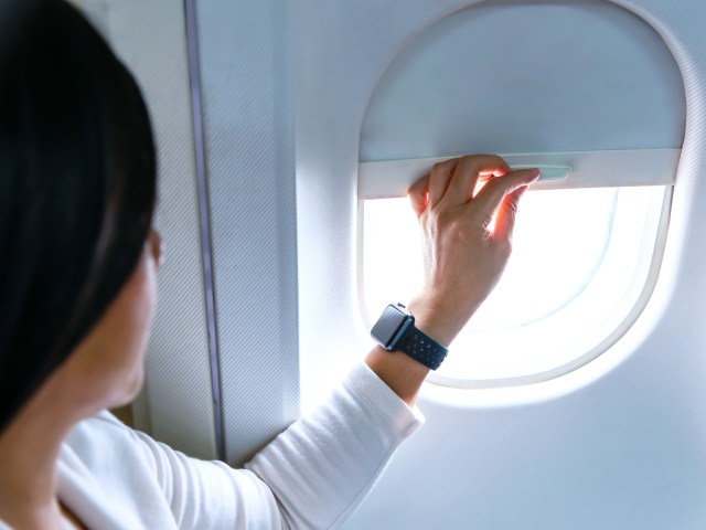 Airline passenger lowering window shade