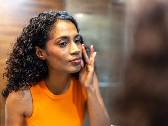 Woman applying sunscreen in mirror