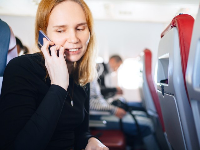 Passenger talking on cellphone in airplane seat