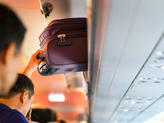 Passenger placing carry-on luggage in overhead bin