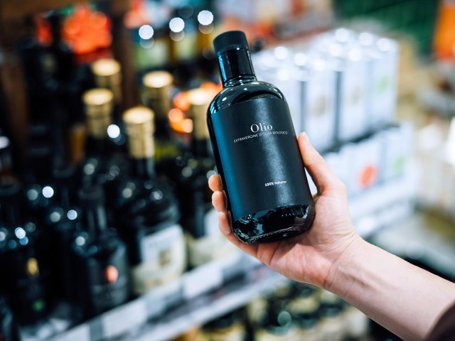 Person holding bottle of olive oil in store