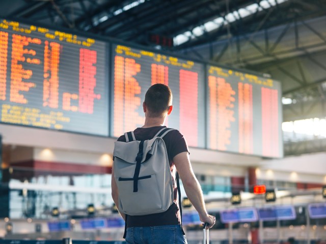 Traveler with backpack looking at airport departures board