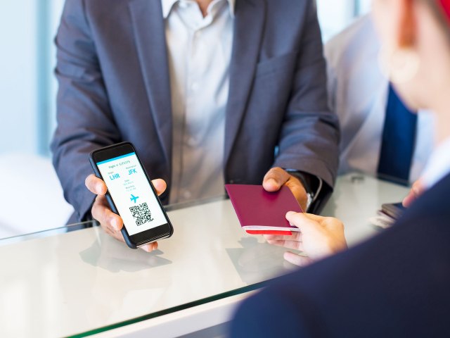 Passenger showing mobile boarding pass and passport to gate agent