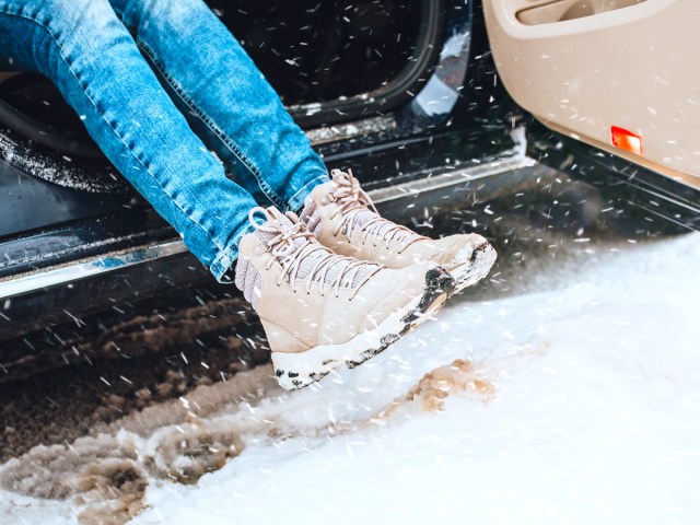 Person wearing boots stepping out of car into snow