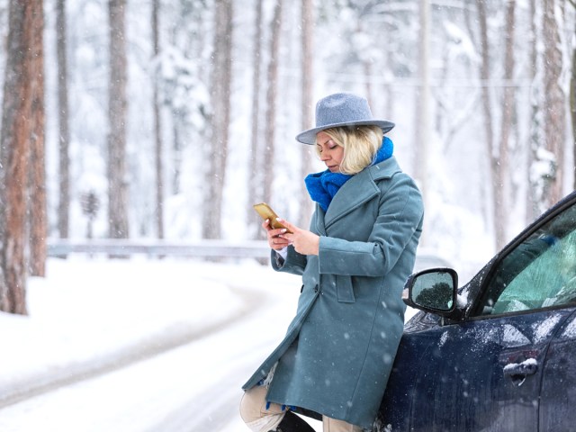 Driver leaning on car on snowy road