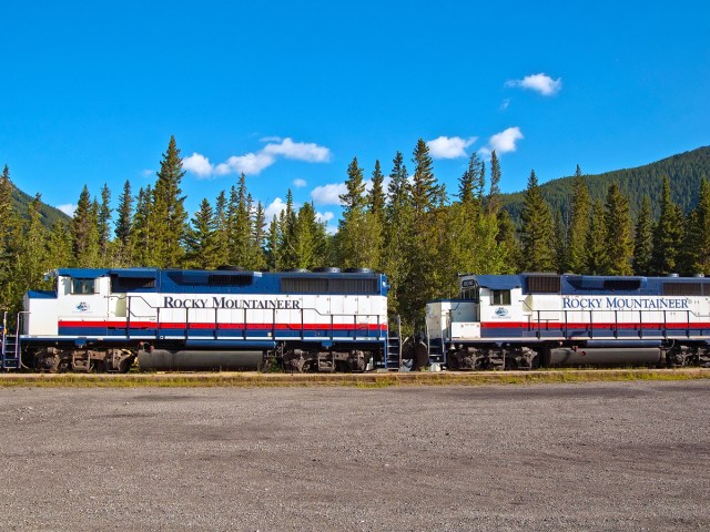 Rocky Mountaineer train on track through forest and mountains