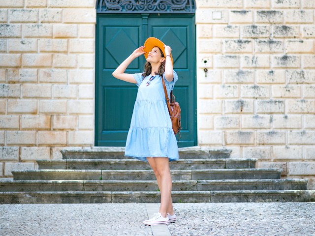 Traveler in hat and dress gazing up at tourist attraction