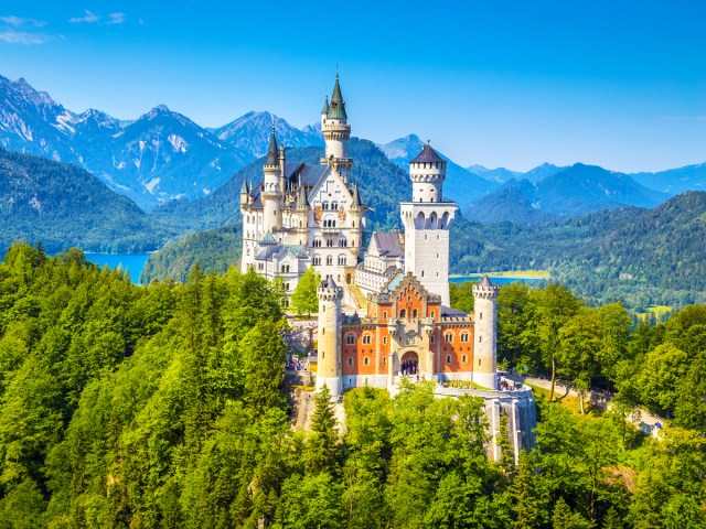 Germany's Neuschwanstein Castle on hilltop surrounded by mountains and lakes