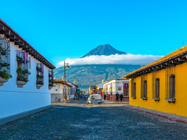 Car driving on street in Guatemala with view of volcano