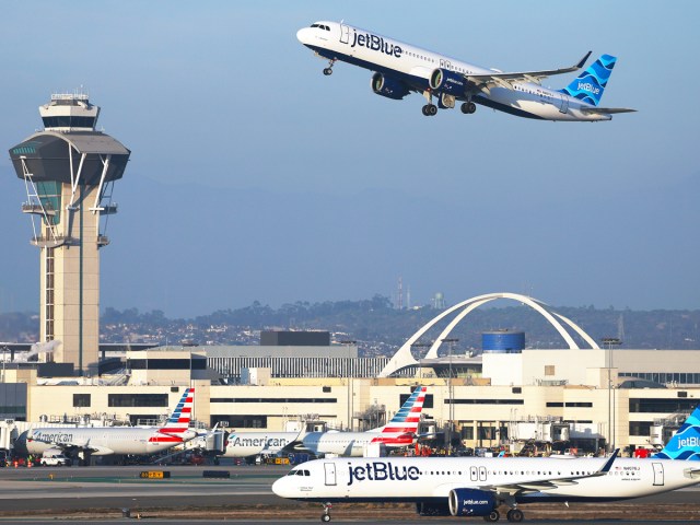 JetBlue Airbus A321NEO departing while another JetBlue aircraft taxies on runway at Los Angeles International Airport