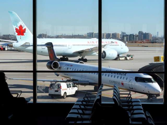 Air Canada CRJ-900 parked at gate while company Boeing 787-8 is towed in background