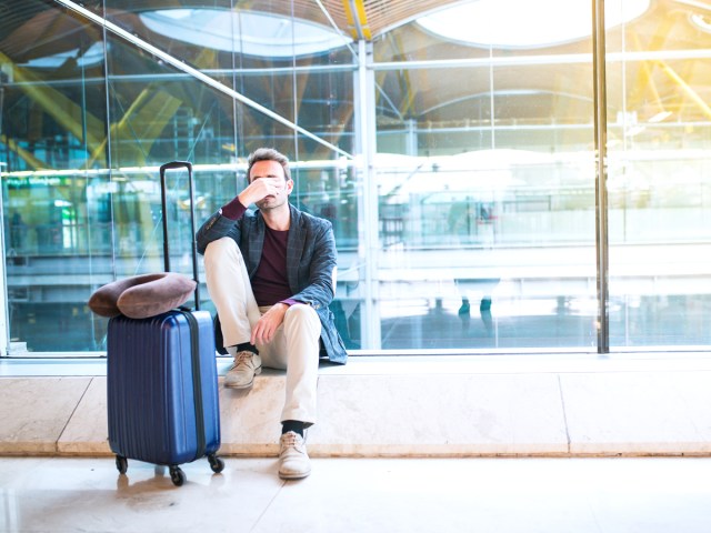 Traveler sitting in airport with suitcase