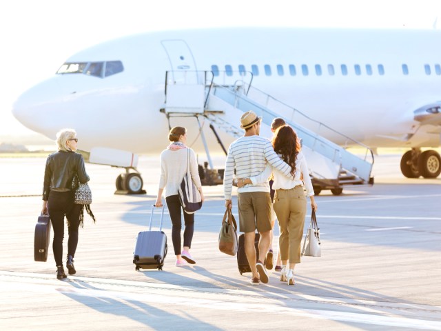 Airline passengers walking across tarmac to board airplane