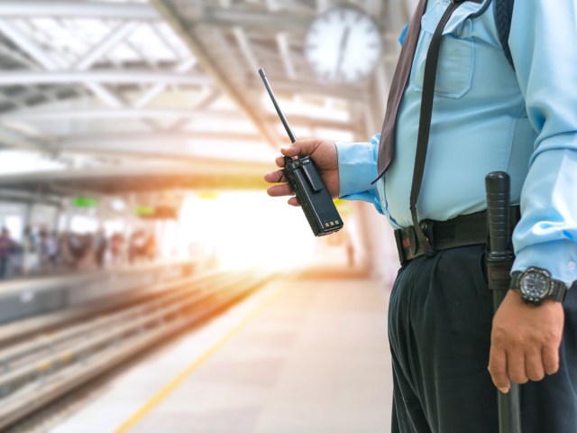 Border agent holding walkie-talkie on train platform