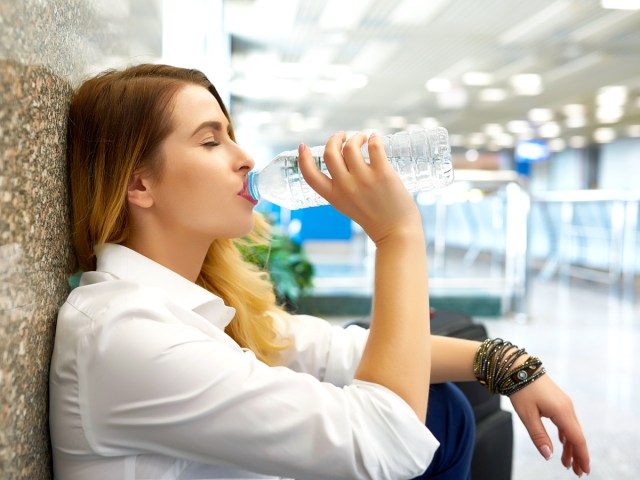 Traveler drinking bottled water in airport terminal