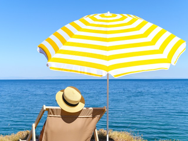 Person sitting under umbrella looking at the ocean