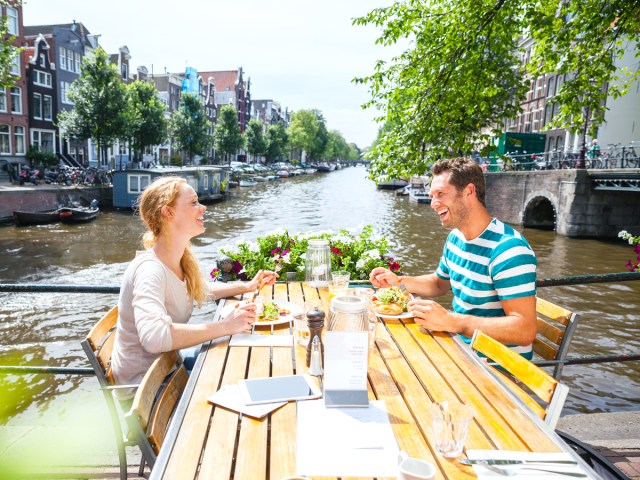 Two people dining alfresco along canal in Amsterdam, Netherlands