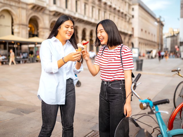 Two people eating ice cream cones on sidewalk