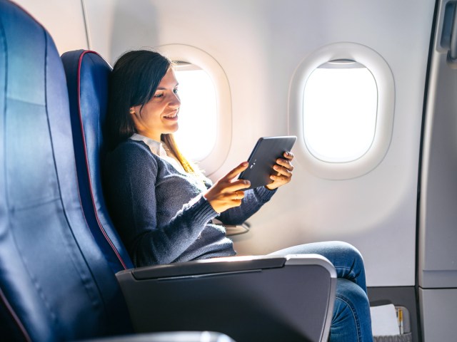 Passenger reading tablet in airplane seat