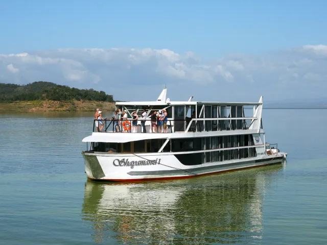 People standing on houseboat deck while it cruises on lake in South Africa