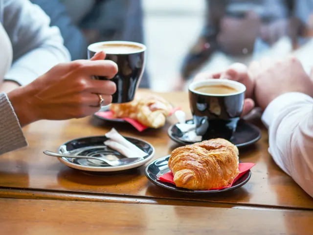 Two people drinking coffee and eating pastries