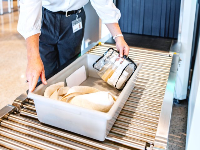 Bin with liquids being examined at airport security checkpoint