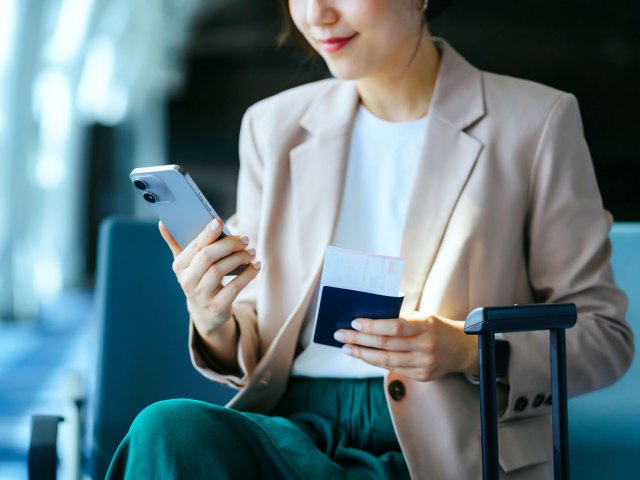 Traveler holding cellphone, passport, and boarding pass