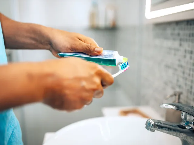 Person squeezing toothpaste onto toothbrush
