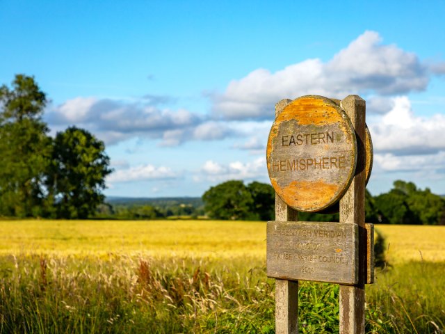 Sign marking the Prime Meridian, with Eastern Hemisphere on one side and Western Hemisphere on the other