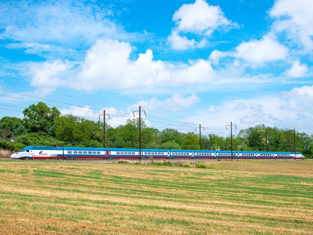 Amtrak train traveling past open field