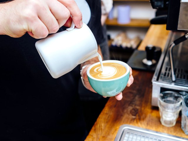 Barista pouring milk into latte