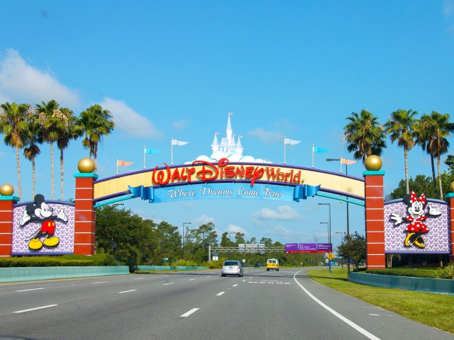 Sign over roadway for Walt Disney World with slogan "Where Dreams Come True"