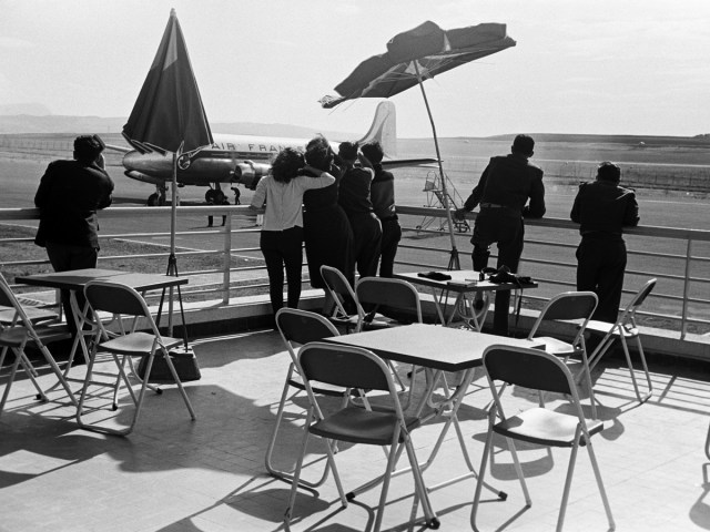Historical photo of people standing on observation deck overlooking airport