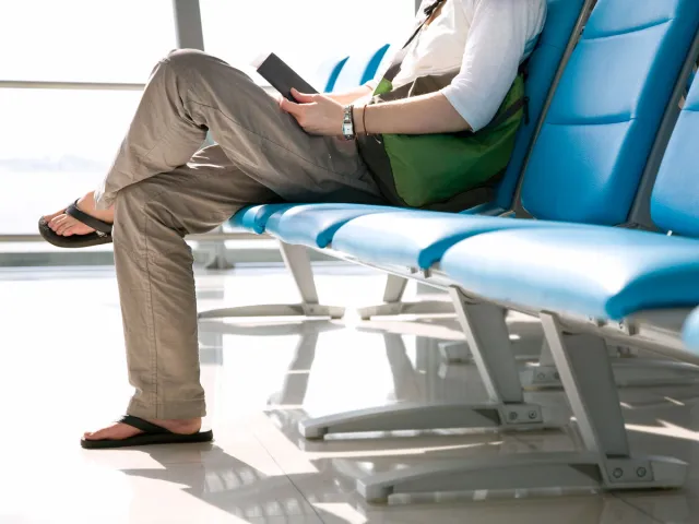 Airline passenger sitting at gate wearing sandals