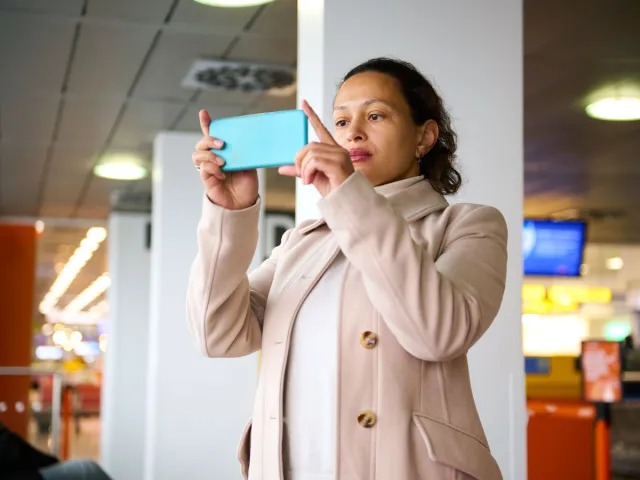 Woman taking cellphone picture in airport