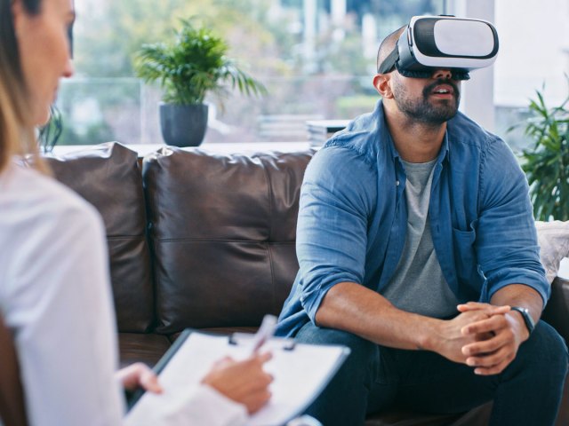 Person wearing VR headset as doctor takes notes