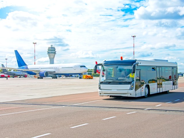 Bus taking passengers across airport tarmac to board plane via air stairs