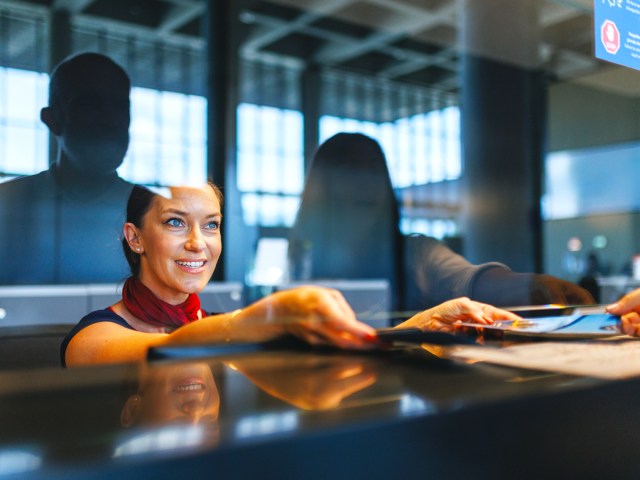 Airport agent handing passenger boarding pass