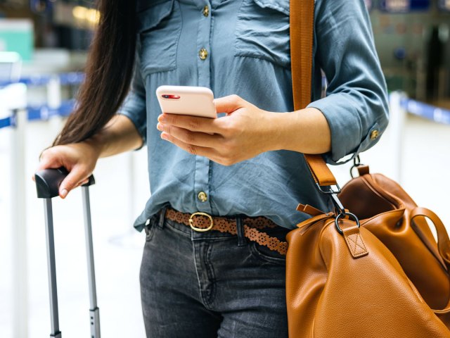 Traveler holding phone with bags in airport